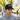 Man wearing Logan D black trucker cap in sunny outdoor park.
