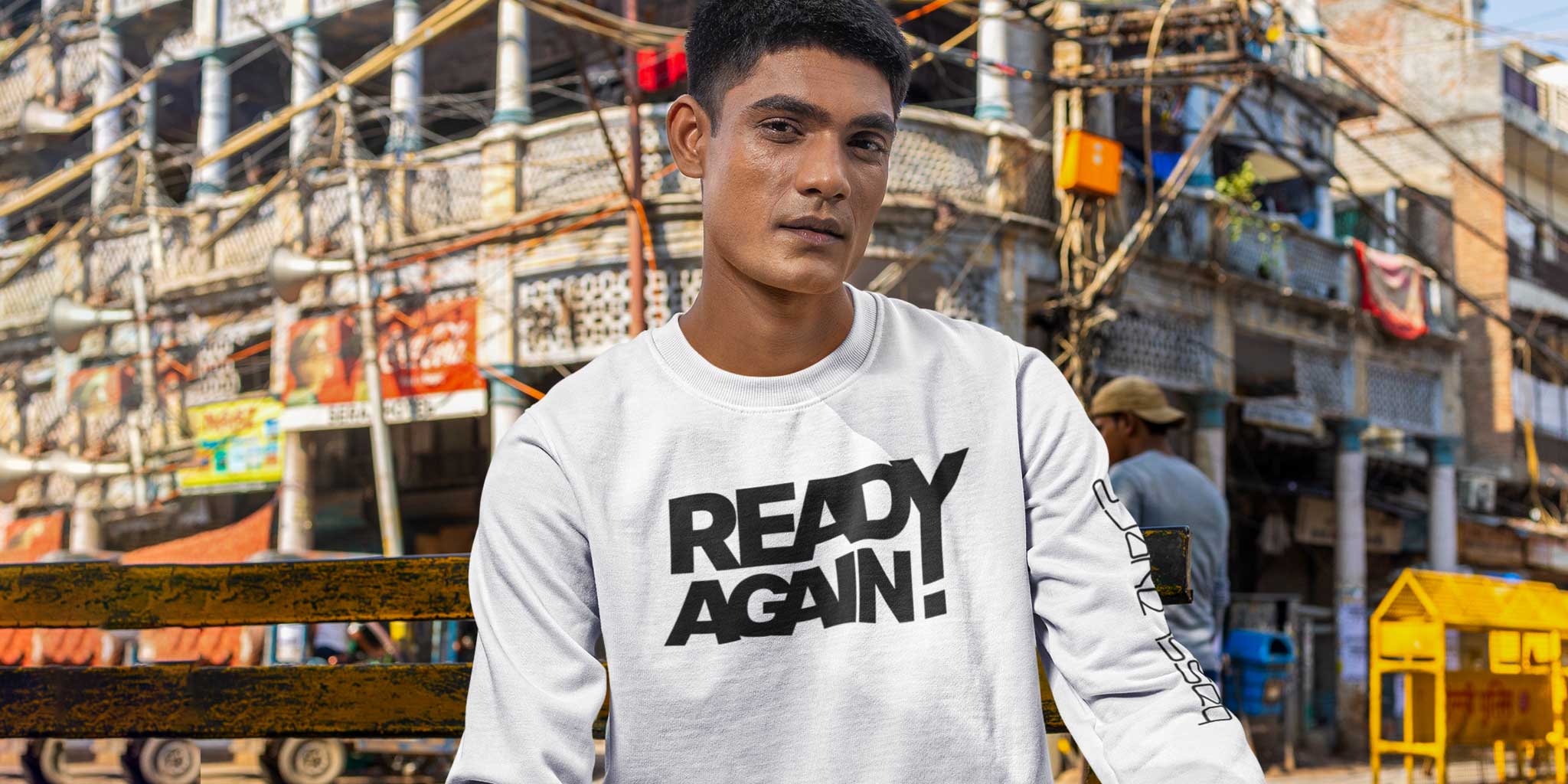 A young man in a city wearing a Basslayerz Ready Again unisex sweatshirt